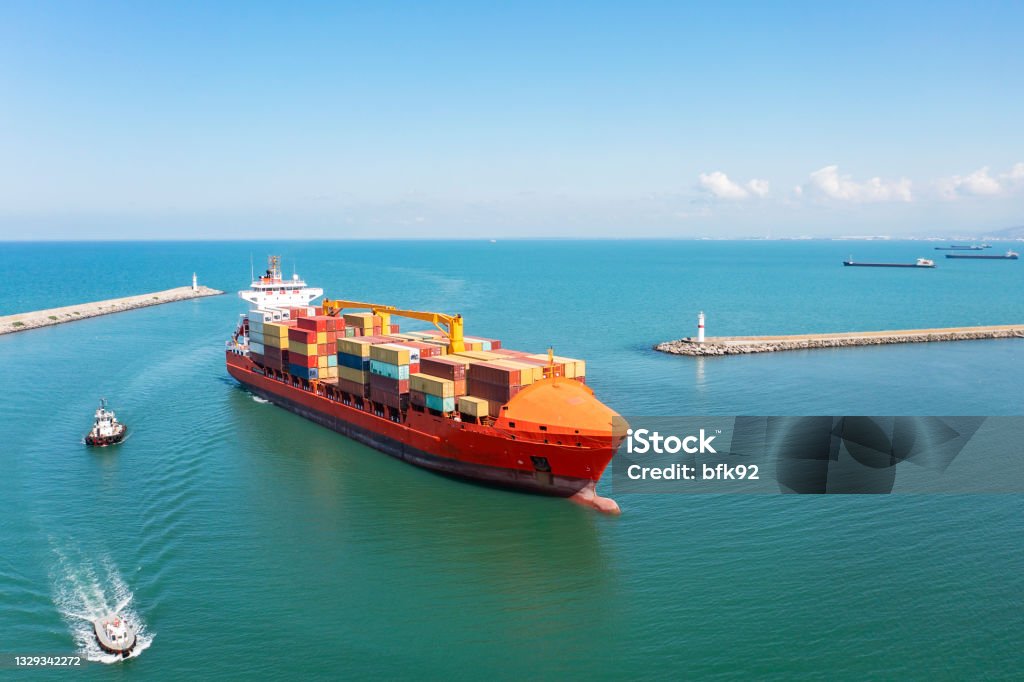 Aerial view of Cargo Container Ship approaching port with tugboat. Harbour tugboat guides a cargo ship into the harbour of Samsun - Turkey - Taken with DJI Mavic 2 Pro, You can see more shipping concept images in my portfolio. Aerial drone view of a container ship nearing port with the assistance of a tugboat Container Ship Stock Photo