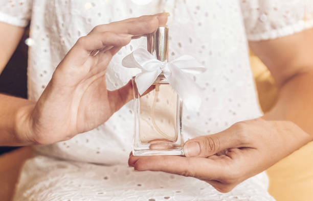 istock Perfume bottle with a white gift ribbon in a female hand 1329344195