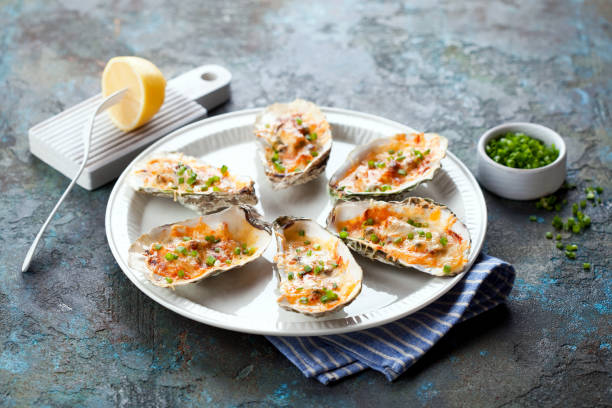 Rockefeller oysters baked with cheese on a plate, a selective focus Rockefeller oysters baked with cheese on a plate, a selective focus seafood gratin stock pictures, royalty-free photos & images