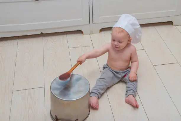 Photo of baby boy in the image of a cook with a spoon and a saucepan