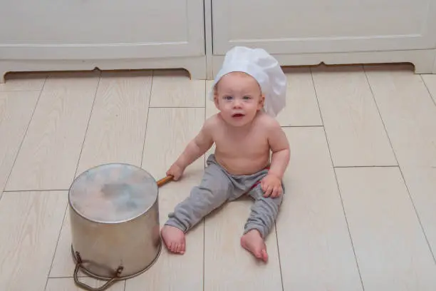 Photo of baby boy in the image of a cook with a spoon and a saucepan