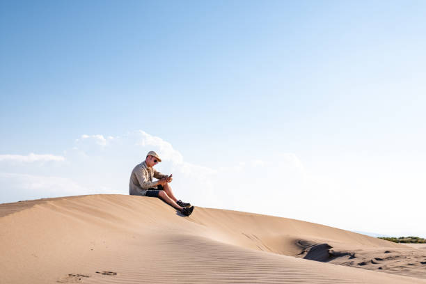 istock Man using smart phone with internet connection in the desert dunes alone 1329348113