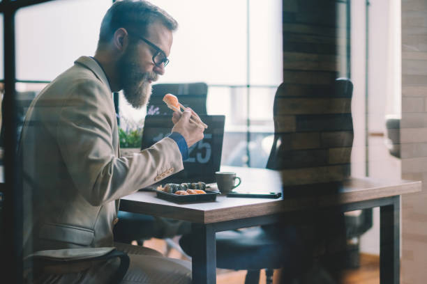 istock Businessman eating sushi in the office 1329351511