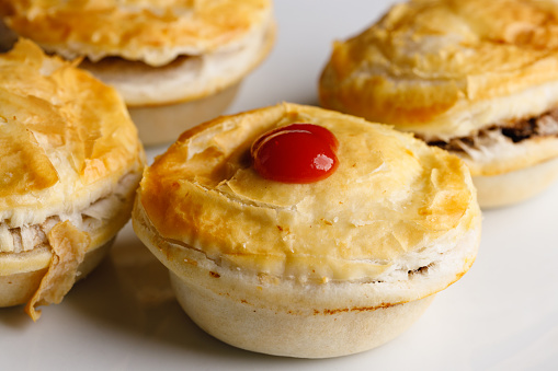 Group of meat pies with tomato sauce.