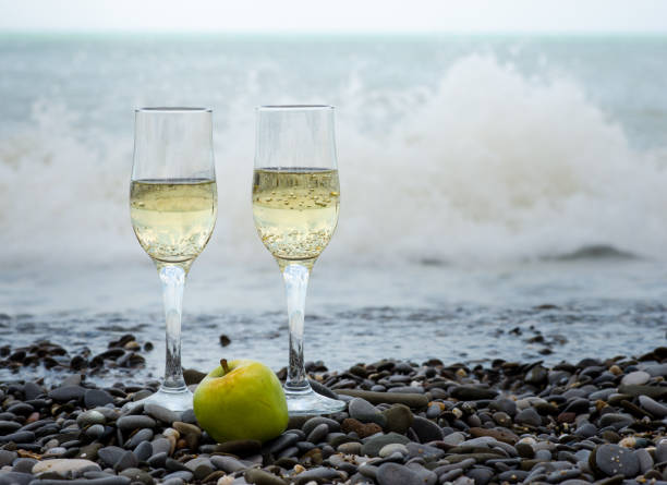 zwei gläser champagner und ein grüner apfel am meer date der jungen - alcohol alcoholism anniversary apple stock-fotos und bilder