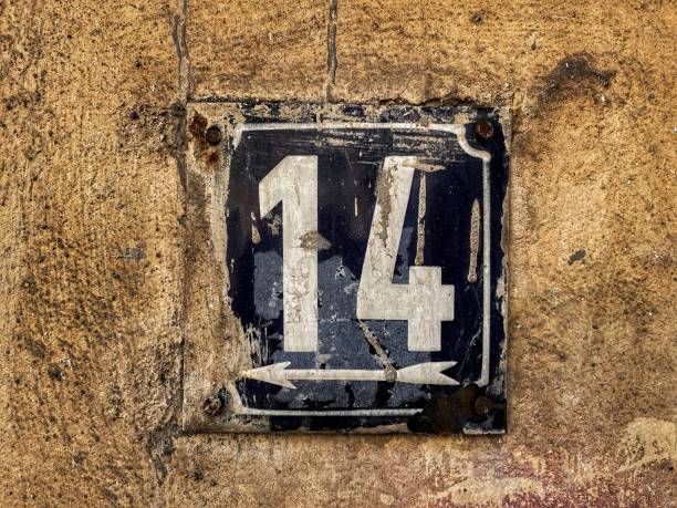istock Old metal plate with number 14 stained with facade paint placed on an old brick wall 1329356072