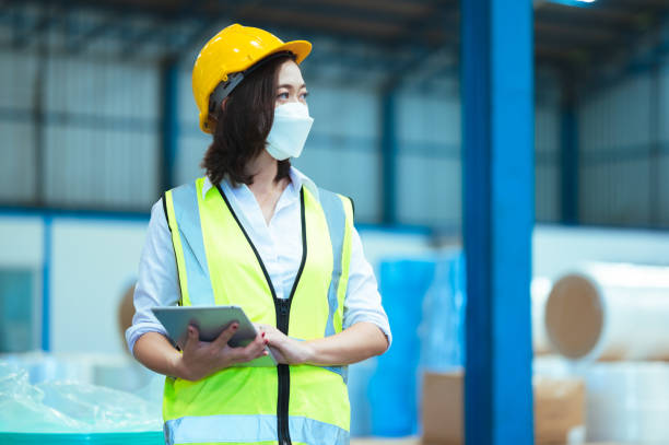 istock Chief industrial engineer inspects the mask factory. portrait woman while using a laptop. They show an assertive demeanor. Protective equipment in the danger zone. 1329357708