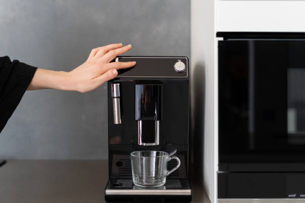 istock Woman pressing button on black coffee machine 1329363972