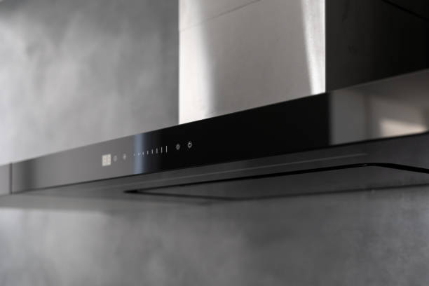 State of art sleek technological black exhaust hood State of art sleek technological black exhaust hood, touch controls marked with white, kitchen appliance in apartment with modern interior, light grey wall in blurred background. Close up shot kitchen hood stock pictures, royalty-free photos & images