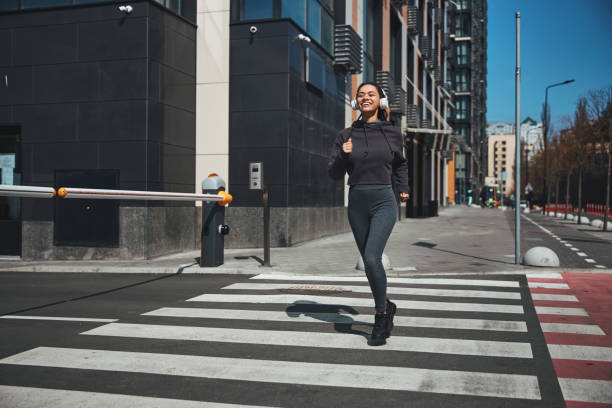 istock Smiling joyful young female runner jogging ahead 1329366089