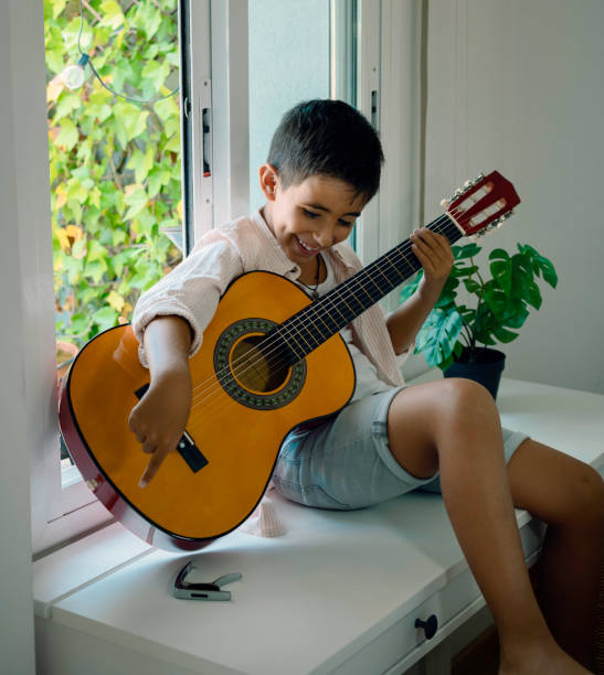 istock Boy practicing guitar in his room by the window 1329369890