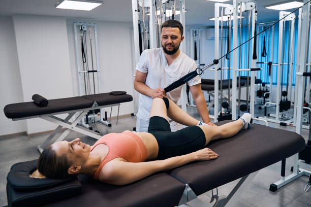 istock Young woman training leg muscles and joints under doctors supervision on massage table 1329370695