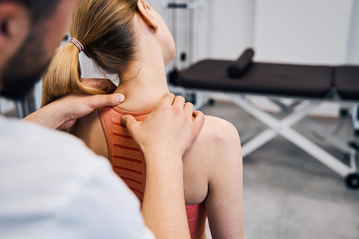 Fisioterapeuta masajeando la mano de la mujer dolorosa cuello en la sala de física primer plano vista hacia atrás. Terapia de recuperación photo