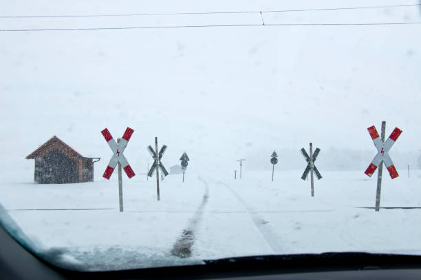 fahren an einem offenen bahnübergang bei starkem schneefall und nebel - drivers point of view country road snowing blizzard stock-fotos und bilder