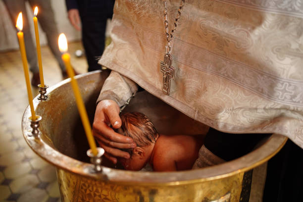 el bebé se baja en la fuente en el bautismo en la iglesia. - ahijado fotografías e imágenes de stock