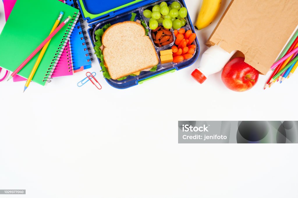 Healthy school lunch with school supplies. Above view top border on a white background. Healthy school lunch with school supplies. Above view top border on a white background. Back to School concept. School Lunch Stock Photo