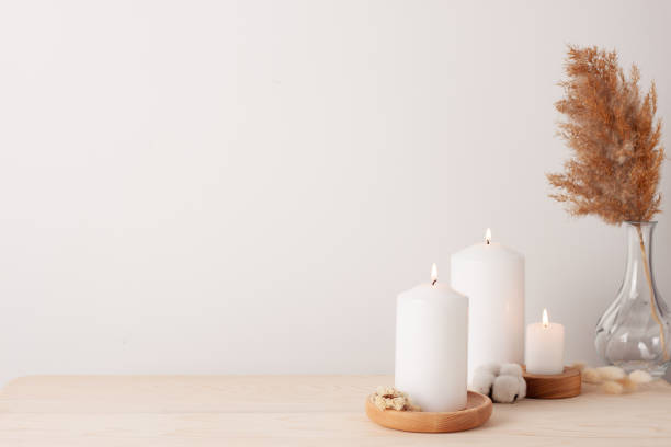 Home decoration with candles and flowers over white wall. Interior design concept. Close up, copy space Home decoration with candles and flowers over white wall. Interior design concept. Close up, copy space hygge photos stock pictures, royalty-free photos & images