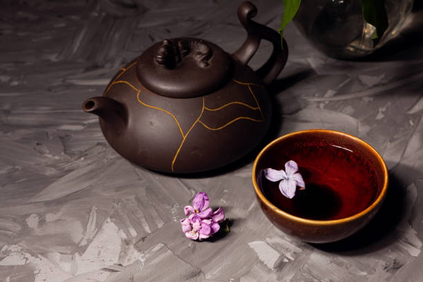 chinese tea. tea bowl and teapot on a dark background. lilac flower floating in tea - província de yunnan imagens e fotografias de stock