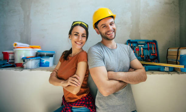 Modern happy young couple in love in casual clothes during new home repair or renovation of walls with a lot of tools for this stock photo