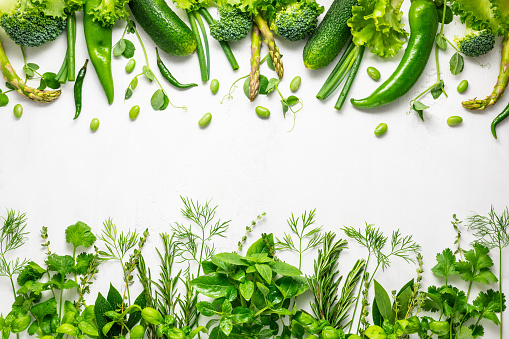 Raw green vegetables and fresh herbs arranged in a frame. Cooking clean eating concept. Healthy food.Top view.