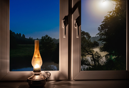 night landscape outside the window moonlight burning kerosene lamp on the windowsill
