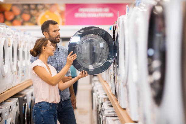 jeune couple à la recherche d’une machine de séchage appropriée - équipement ménager photos et images de collection