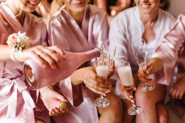 jeunes demoiselles d’honneur qui clignotent avec des coupes de champagne dans la chambre d’hôtel. photo en gros plan de filles joyeuses célébrant un enterrement de vie de jeune fille. les femelles portent un toast avec du vin. - bachelor home photos et images de collection