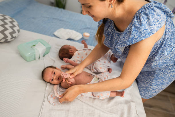 istock Mother changing twin babies clothes at home 1329393448