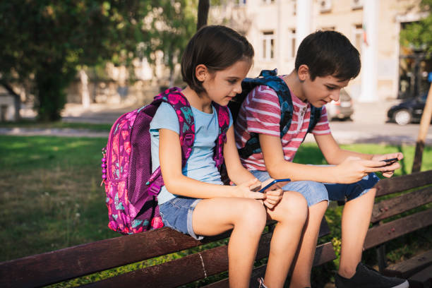 istock Back to school. Happy kids using digital mobile phone outdoors. 1329398159