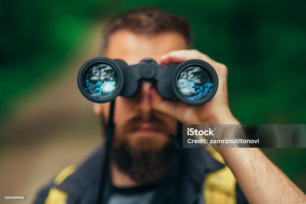 Binoculars being used by a male hiker while spending time in the nature Close shot of a binoculars being used by a male hiker while spending time in the nature Binoculars Stock Photo