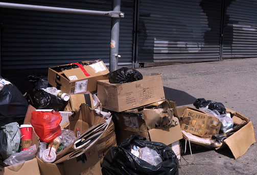 pile of trash, in front of closed  up stores, on the sidewalk in Chinatown, Manhattan, NYC