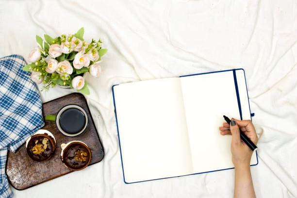 istock hand write on empty agenda book or notebook and cup of hot coffee with macarons, flowers pot and pillow on white bed 1329403182