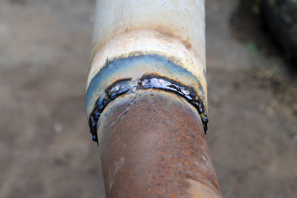 istock Welded butt joint with some defects. Rusty brown metal pipe and white painted one welded together 1329411389