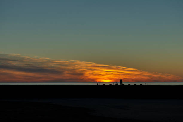 istock Fisherman silhouette at sunrise on breakwater 1329414603