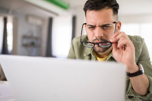 istock Young man with eye sight issues making effort to see the screen. 1329419858