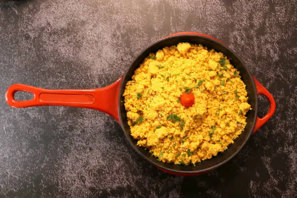 red iron pot with Farofa. Traditional Brazilian food. On a dark background.