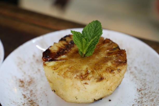 istock Grilled pineapple on the barbecue, with grill marks and cinnamon on top. on a white plate 1329420749
