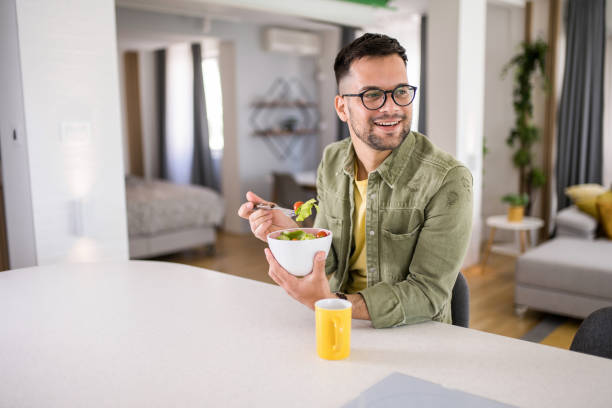 istock Young man eating a salad at home. 1329420800
