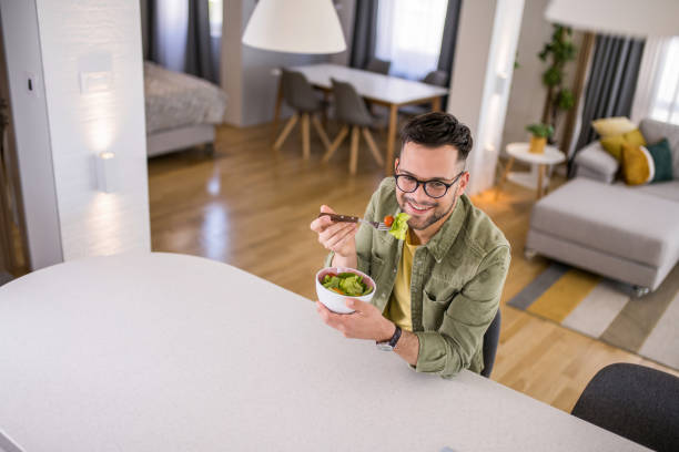 istock Young man eating a salad at home. 1329420820