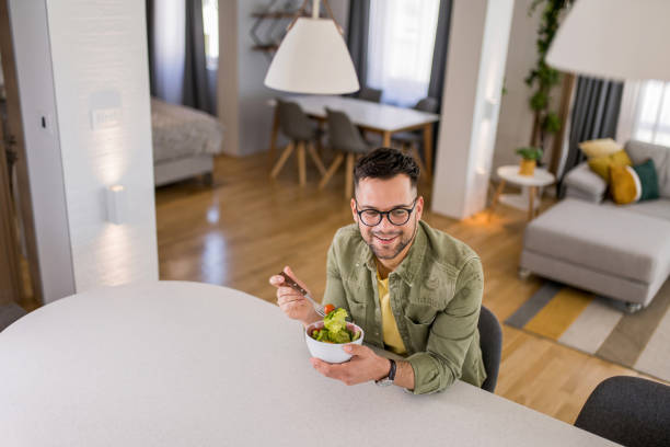 istock Young man eating a salad at home. 1329420826