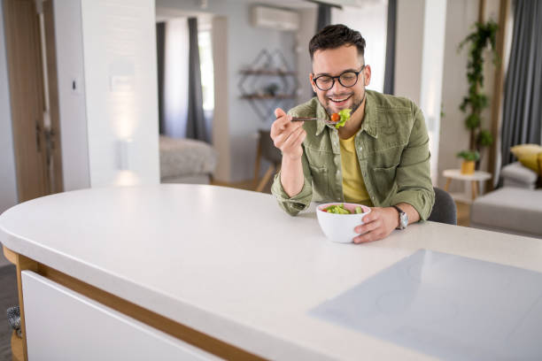 istock Young man eating a salad at home. 1329420838