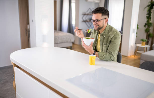 istock Young man eating a salad at home. 1329420846