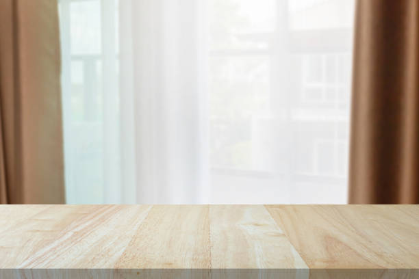 istock Empty wood table top with window curtain abstract blur background for product display 1329424094