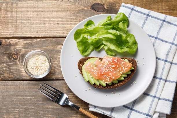 pane di segale integrale toast con salmone e avocado su sfondo tavolo in legno. - smoked salmon cooking copy space food foto e immagini stock