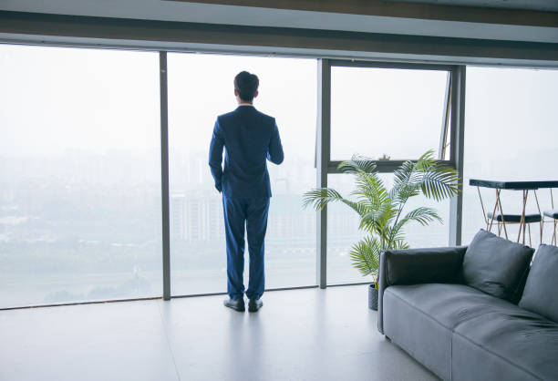istock Young businessman looking out of window at office 1329442949