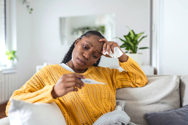 istock Sickness, seasonal virus problem concept. Woman being sick having flu lying on bed looking at temperature on thermometer. Sick woman lying in bed with high fever. Cold flu coronavirus, covid19 1329443511