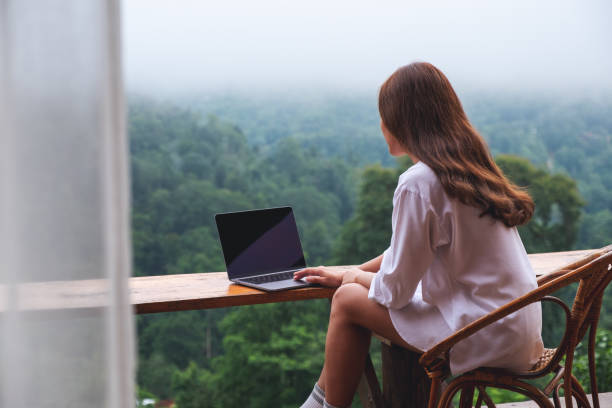 istock a woman using and working on laptop computer while sitting on balcony with a beautiful nature view on foggy day 1329445651