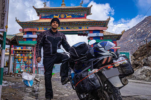 solo young bike ridder man with his loaded bike at mountain pass at day from flat angle image is taken at sela pass tawang arunachal pradesh india. it is one of the highest passes.