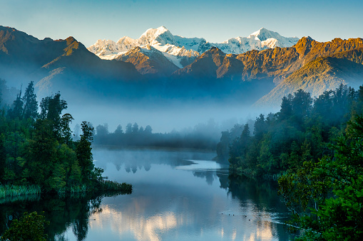 Mist at dawn  preventing the reflections of the snow capped southern alps on the calm water at Lake Matheson