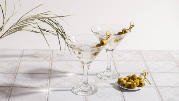 koktajl martini z oliwkami na wyłożonym kafelkami stole. alkoholowy klasyczny napój z lodem w eleganckim szkle - gin tonic water martini olive zdjęcia i obrazy z banku zdjęć